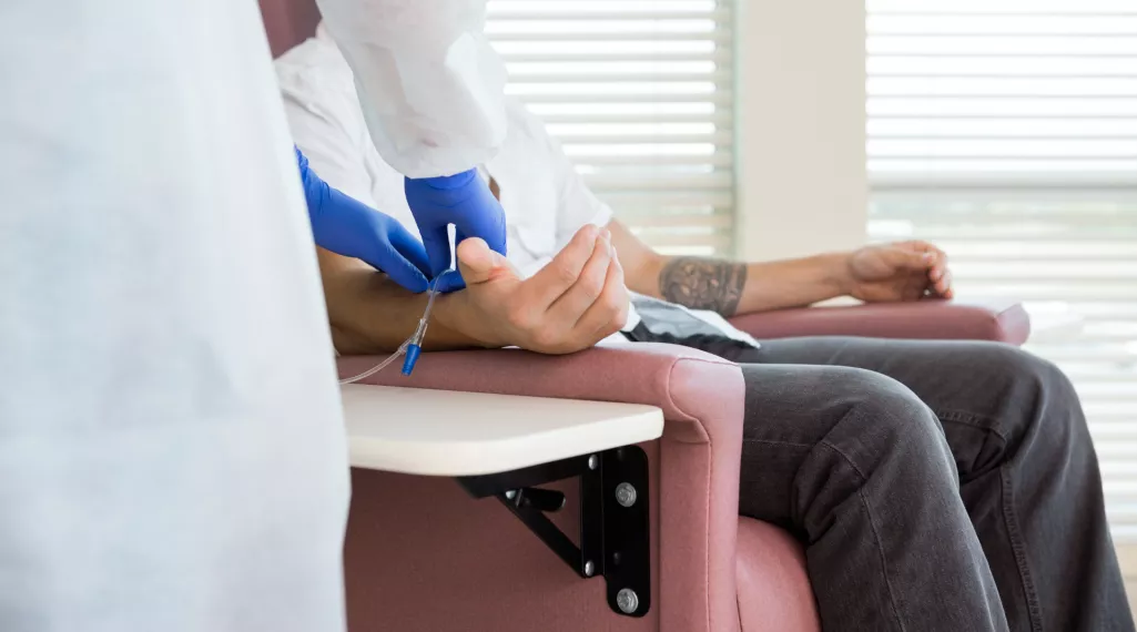 A man in a chair undergoes chemotherapy treatment. 