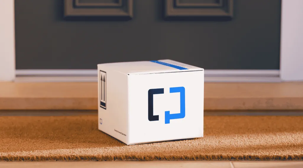 A Cologuard test kit box sitting on a woven doormat at a residential front door, with "this side up" arrows and a "Human Specimen" label printed on the box.
