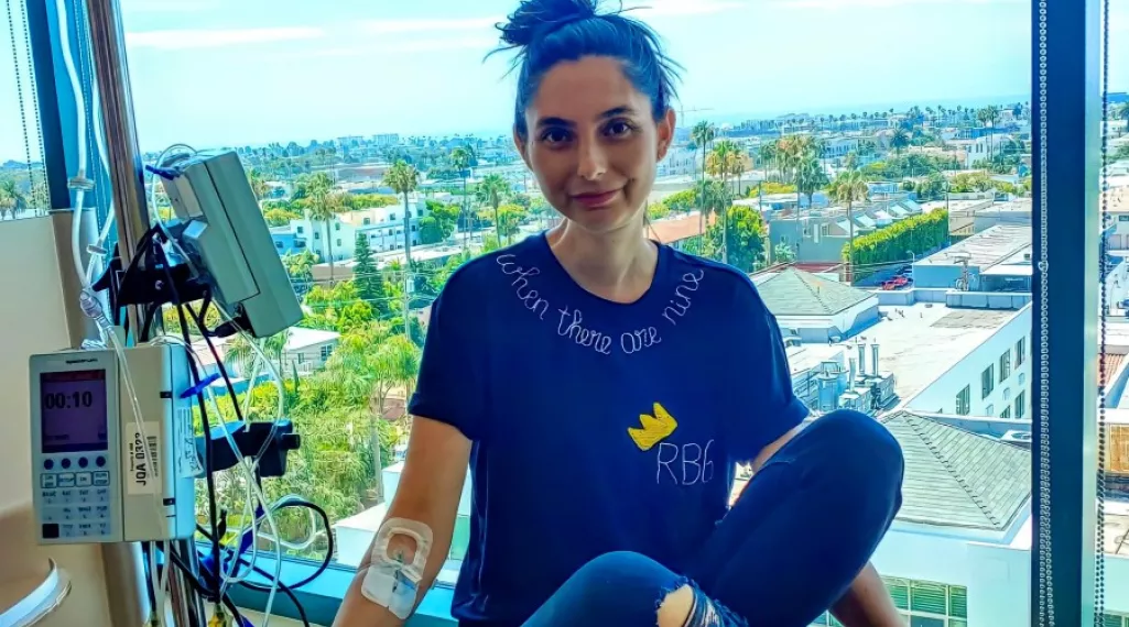 Elizabeth sitting next to a chemotherapy machine. 