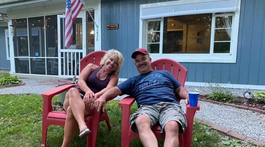 Laura Cain and her husband relax in red Adirondack chairs. 