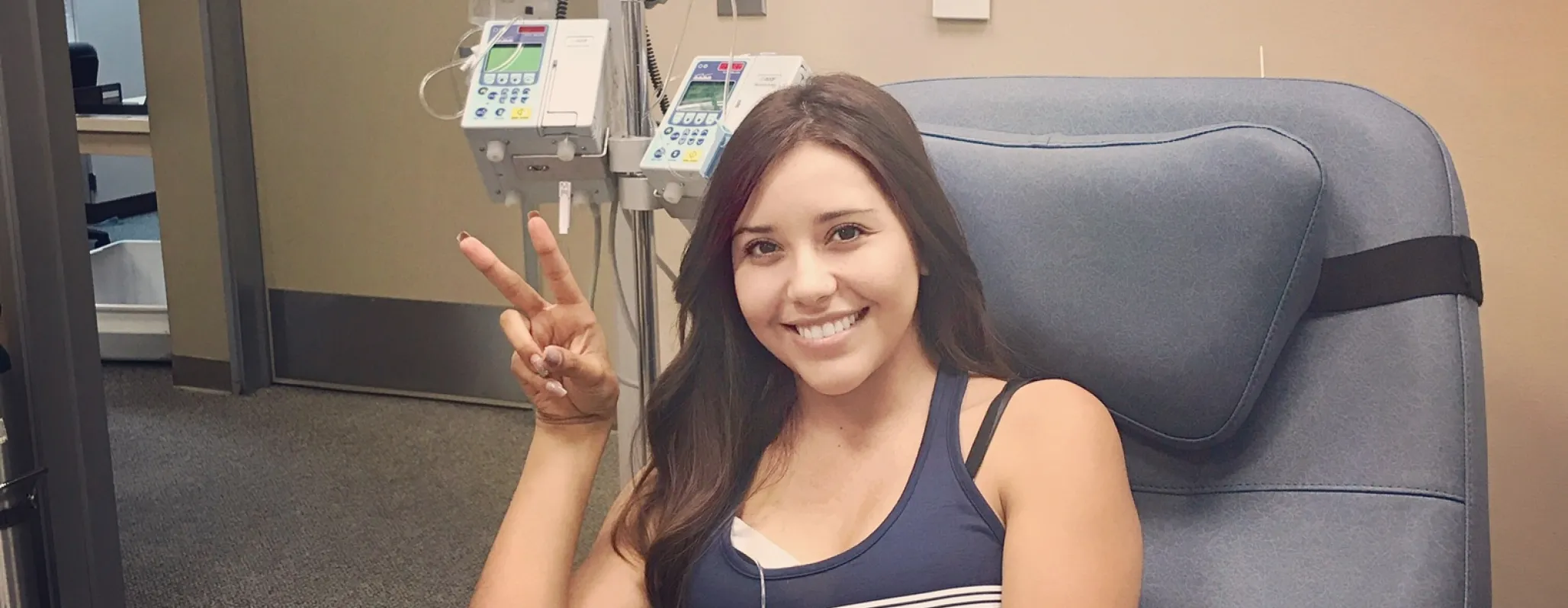 Woman giving peace sign in chemo chair