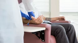 A man in a chair undergoes chemotherapy treatment. 