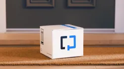 A Cologuard test kit box sitting on a woven doormat at a residential front door, with "this side up" arrows and a "Human Specimen" label printed on the box.