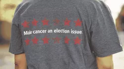 An image of the back of a T-shirt, which has written on it, "Make cancer an election issue." 