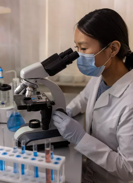 female scientist with vials using a microscope