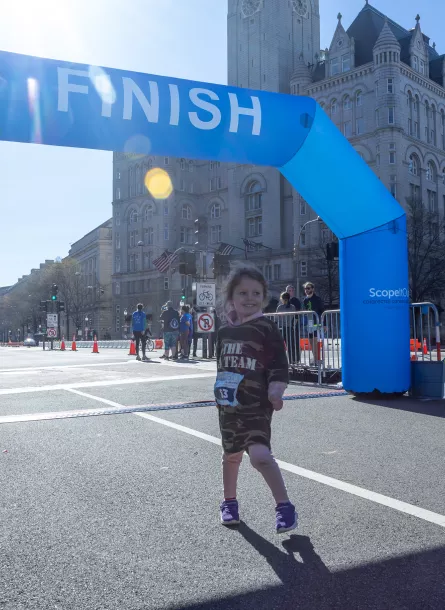 Little girl smiling in front of finish line