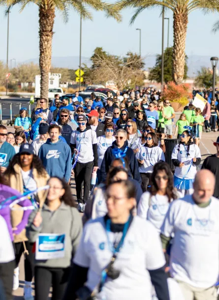 Large group walking at event with palm trees
