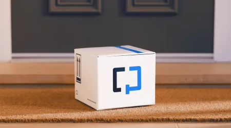 A Cologuard test kit box sitting on a woven doormat at a residential front door, with "this side up" arrows and a "Human Specimen" label printed on the box.