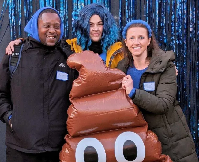 Three people with poop emoji at an event