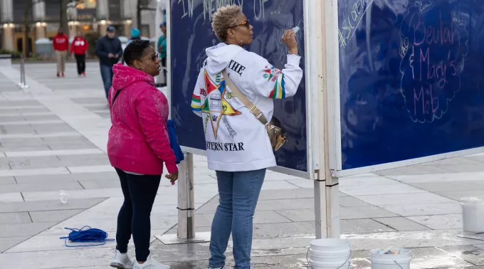 Two Black women writing on chalk board