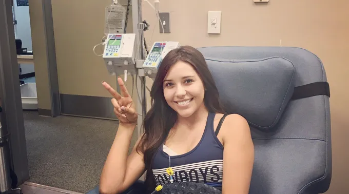 Woman giving peace sign in chemo chair