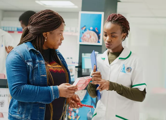 black woman receiving medicine from black female pharmacist