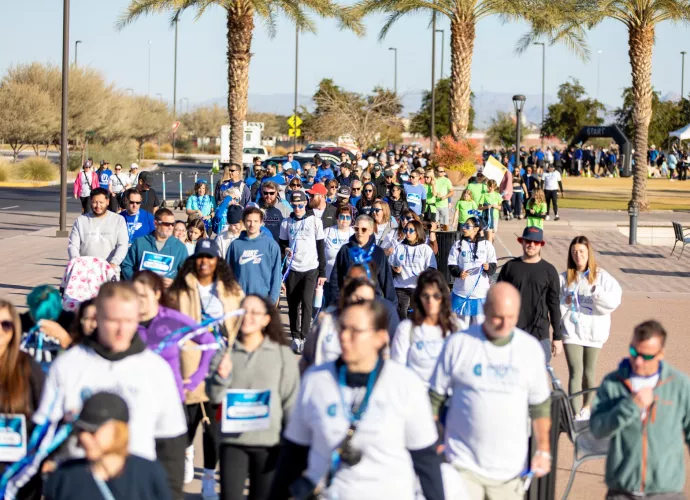 Large group walking at event with palm trees