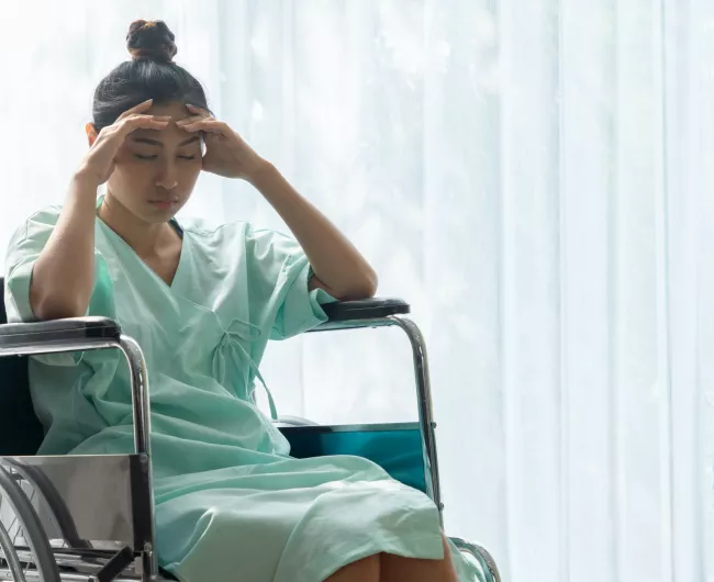 Asian female in a wheelchair with a headache