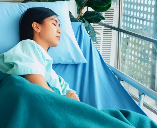 Asian female patient asleep in hospital bed