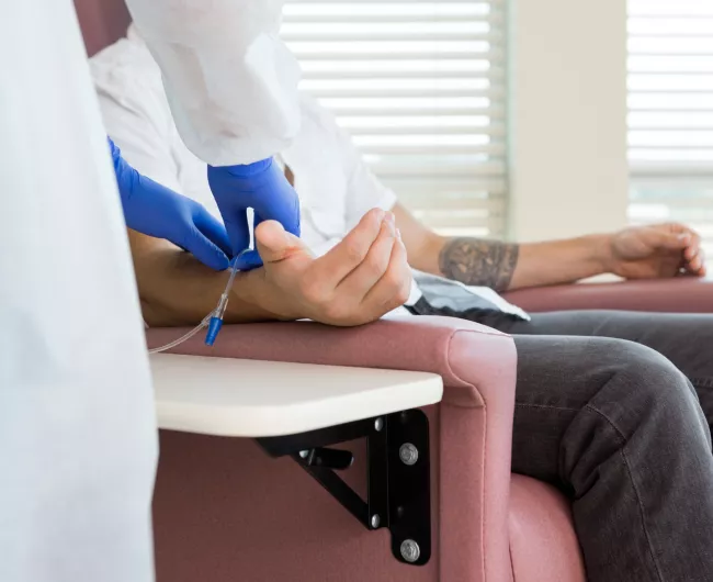 A man in a chair undergoes chemotherapy treatment. 