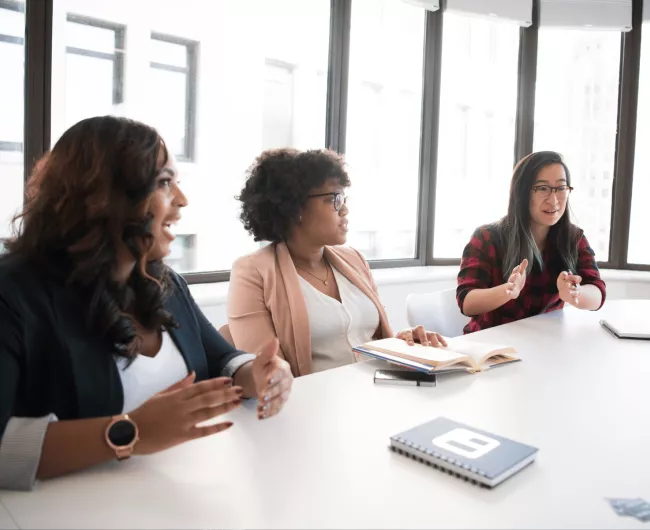 Women professionals speaking at conference table