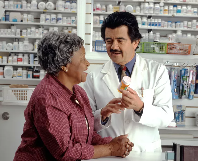 hispanic male doctor prescribes meds to an elderly black woman