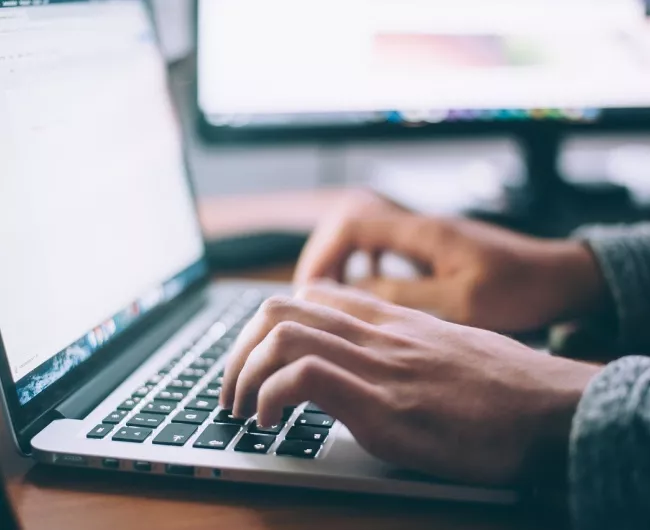 With only their hands visible, a person uses a laptop computer.