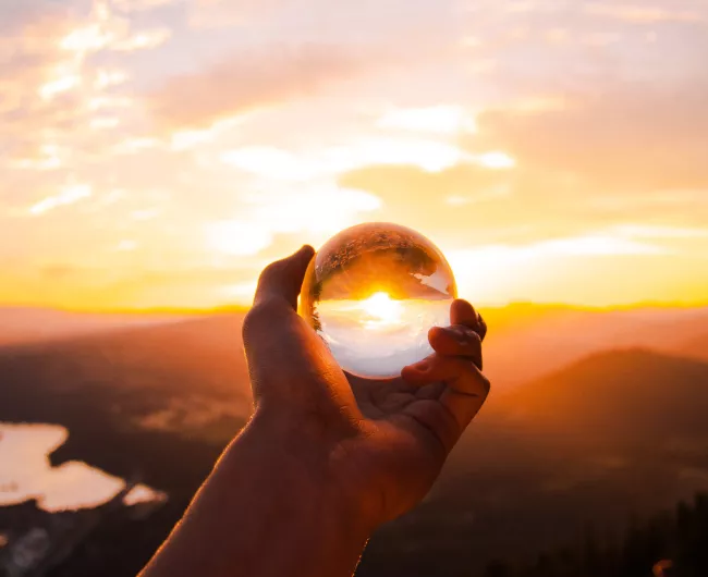 hand holding crystal ball at horizon