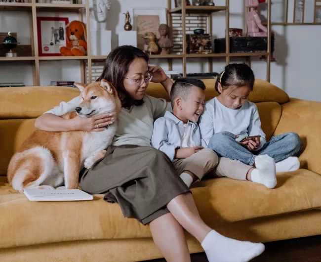 asian woman on couch with dog and young children