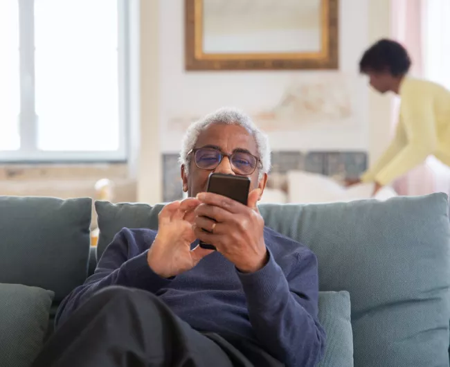 older man on couch with cell phone