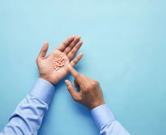 man holding pink pills