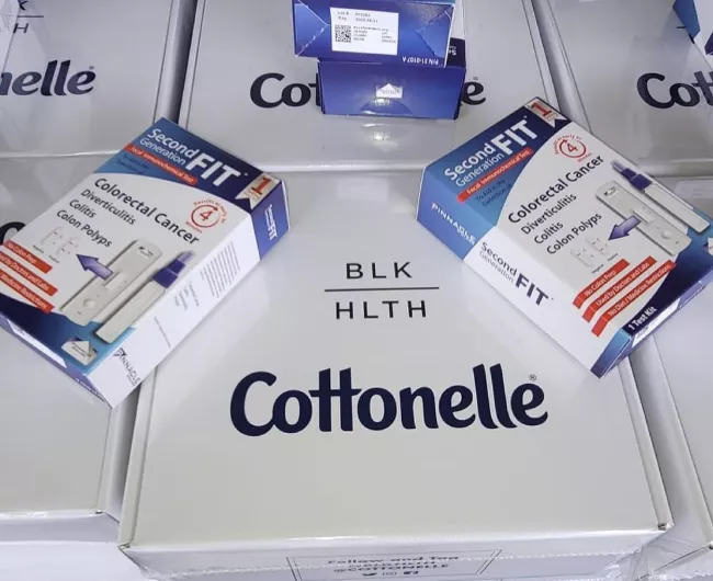A collection of FIT colon cancer screening test kits with the BLKHLTH and Cottonelle logos on them.