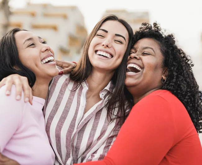 three woman laughing and hugging