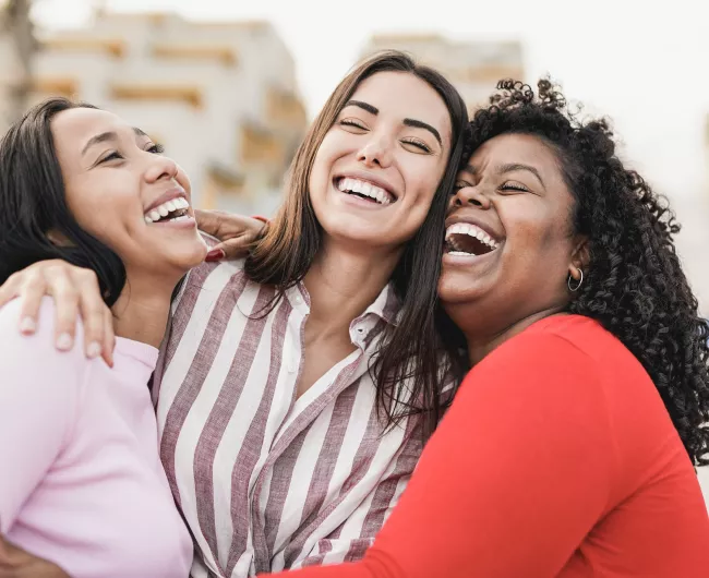 Tres mujeres riendo y abrazándose