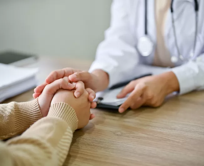 two woman with hands on table talking