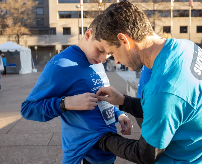 Man helps their son pin their bib