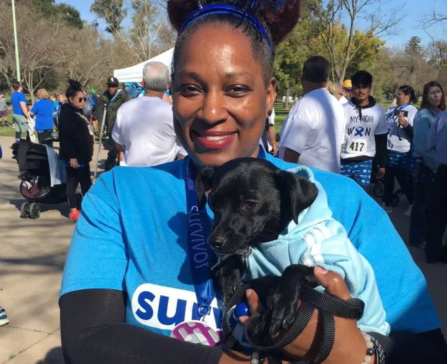 Black woman CRC survivor posing with black dog