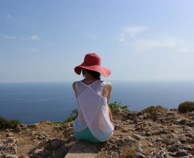 woman sitting on mountain looking at ocean