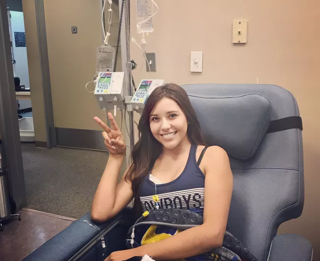 Woman giving peace sign in chemo chair