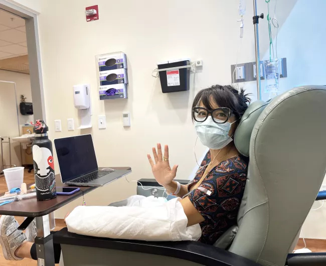 Woman waving in chemo chair