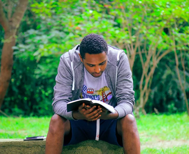 young black man reading in the park