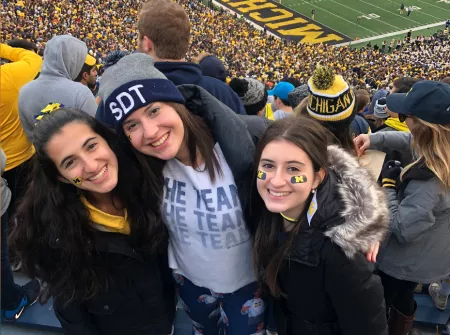 Girl at football game posing with friends